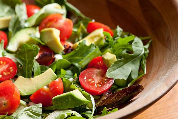 A garden salad with lettuce,  avocado slices, and garden fresh tomatoes